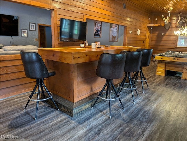 bar featuring dark hardwood / wood-style floors, wood walls, wooden counters, and wooden ceiling