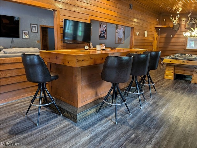 bar with a dry bar, wooden walls, wood ceiling, and wood finished floors