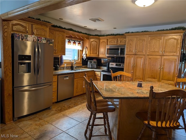 kitchen featuring a center island, sink, a kitchen bar, decorative backsplash, and stainless steel appliances