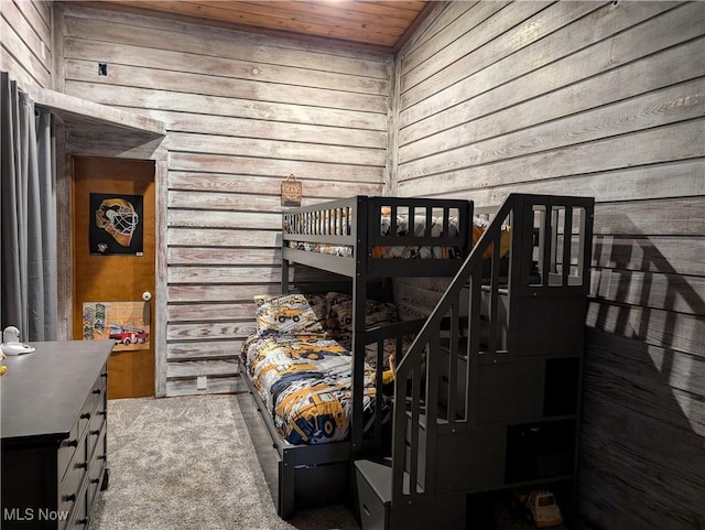 carpeted bedroom with wood walls and wood ceiling