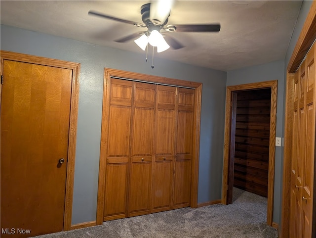 unfurnished bedroom with dark colored carpet, ceiling fan, and multiple closets