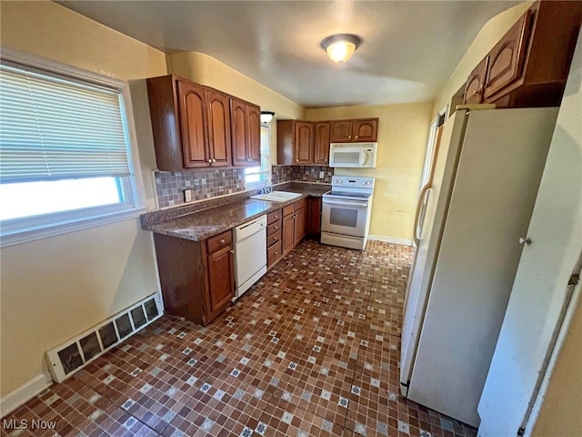 kitchen featuring backsplash, sink, and white appliances