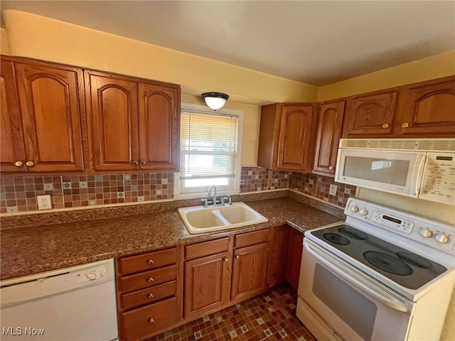 kitchen with dark tile patterned flooring, sink, white appliances, and decorative backsplash