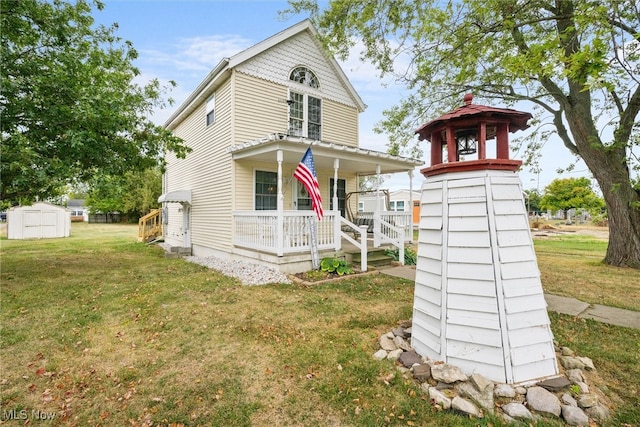 rear view of house featuring covered porch, a lawn, and a storage unit