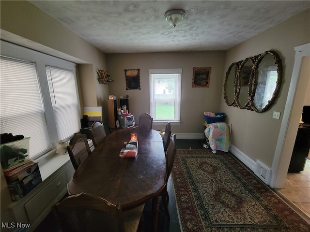 dining area with light tile patterned floors and a textured ceiling