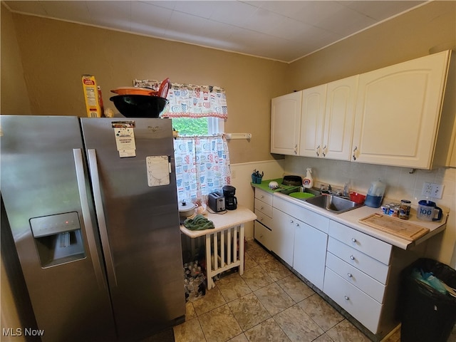 kitchen featuring white cabinets, backsplash, light tile patterned floors, sink, and stainless steel fridge