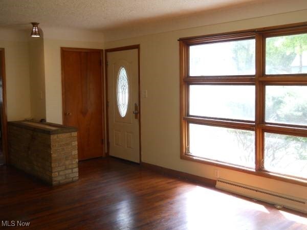 entryway featuring a baseboard heating unit, dark hardwood / wood-style flooring, and a textured ceiling