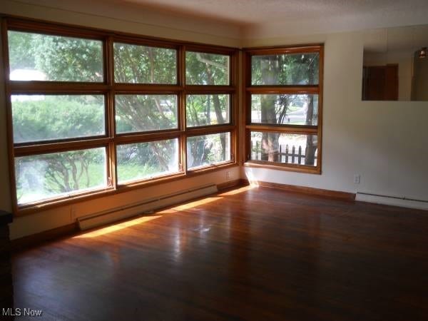 spare room featuring dark wood-type flooring and baseboard heating