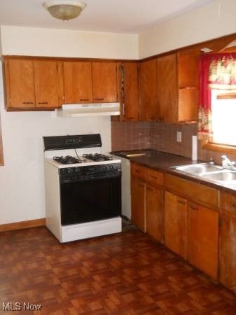 kitchen featuring gas range gas stove, sink, decorative backsplash, and dark parquet floors