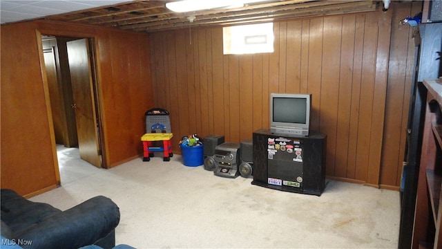 basement featuring light carpet and wooden walls