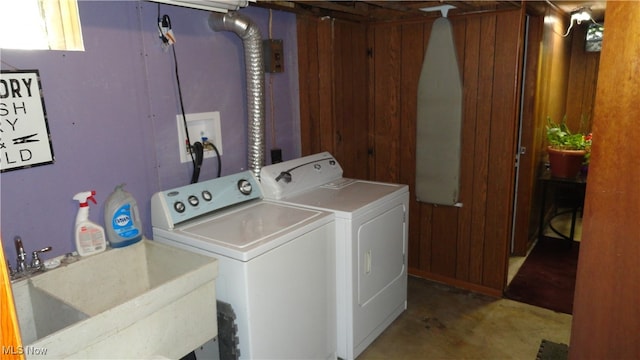 laundry area with wooden walls, sink, and washer and dryer