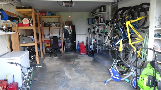 garage featuring black refrigerator, a garage door opener, and white fridge