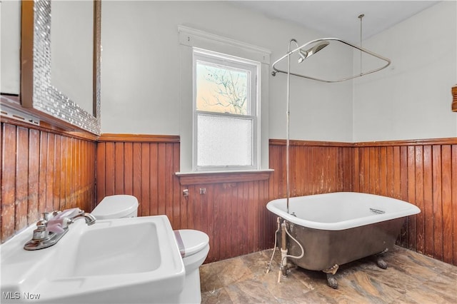 bathroom featuring sink, a healthy amount of sunlight, and wooden walls