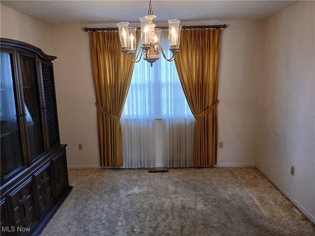 unfurnished room featuring a notable chandelier and carpet flooring