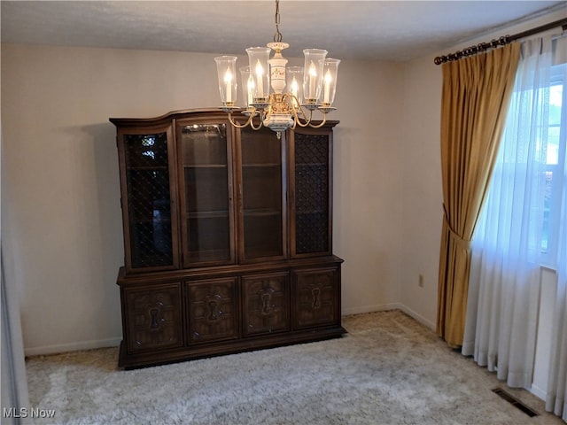 unfurnished dining area with an inviting chandelier and light colored carpet