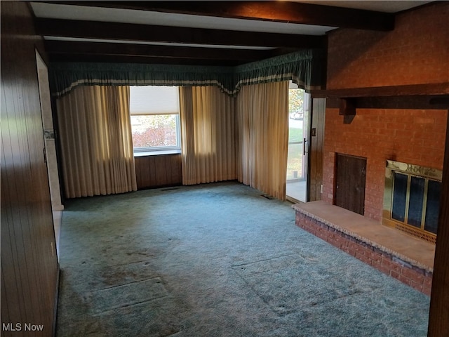 unfurnished living room with a fireplace, beamed ceiling, carpet, and wooden walls