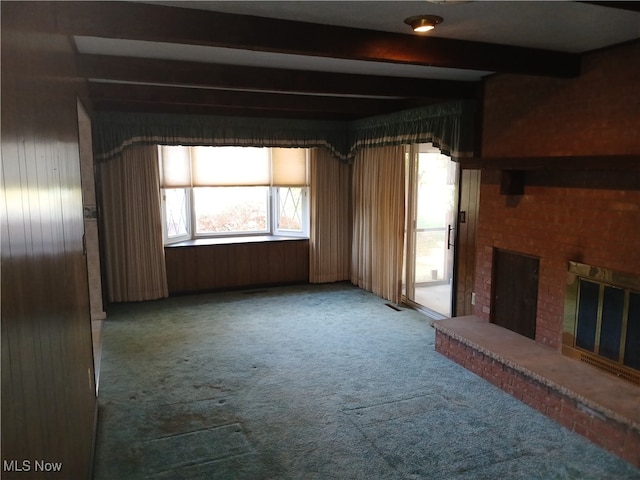 unfurnished living room featuring beam ceiling, a fireplace, carpet floors, and wood walls