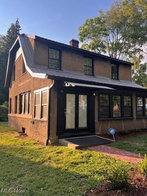 rear view of property with a yard, metal roof, and a chimney