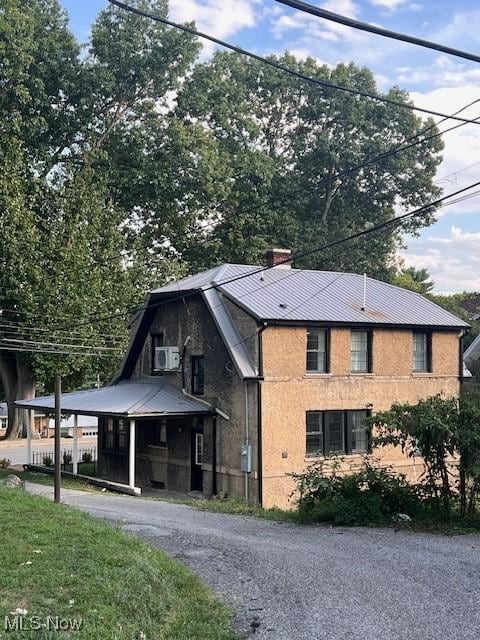 view of front facade with brick siding, a chimney, and metal roof