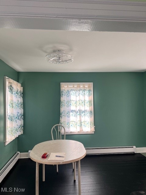 dining area featuring a baseboard heating unit and hardwood / wood-style flooring