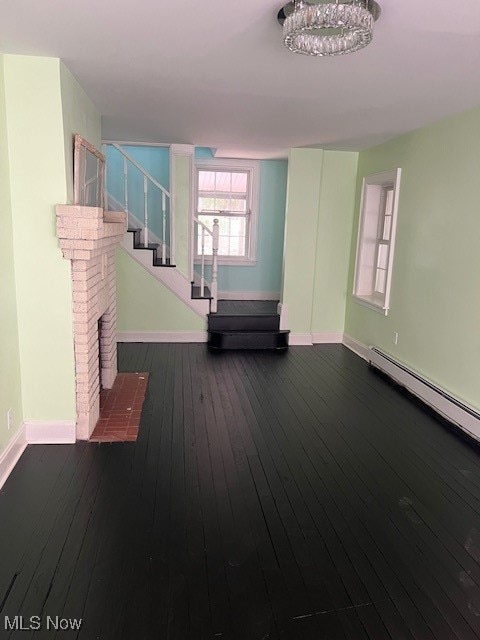 interior space featuring stairs, baseboard heating, baseboards, and wood-type flooring