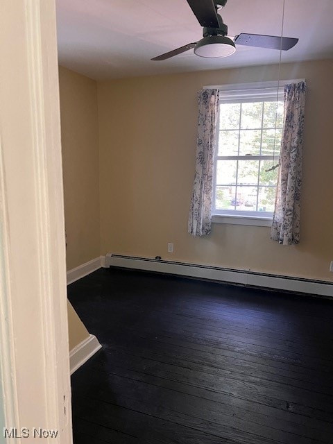 spare room featuring a ceiling fan, dark wood-style floors, baseboards, and a baseboard heating unit