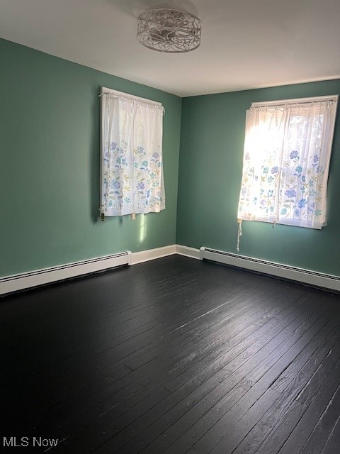 spare room with a baseboard radiator, baseboards, and dark wood-style flooring