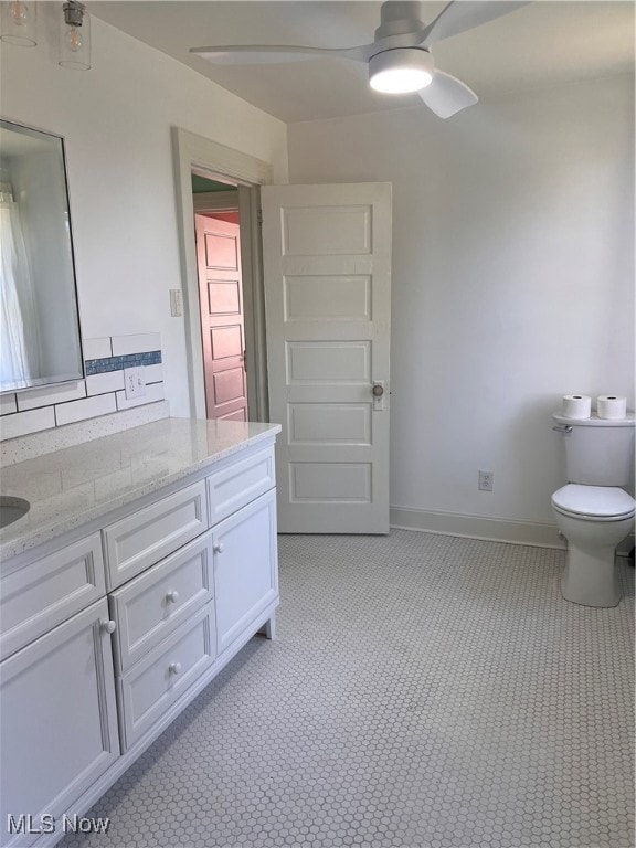 bathroom featuring vanity, toilet, baseboards, and ceiling fan