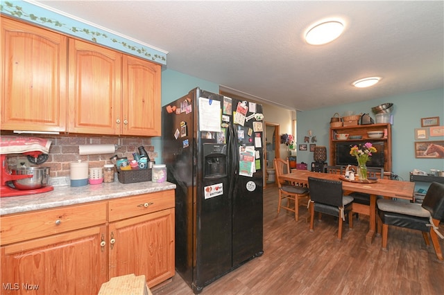 kitchen with a textured ceiling, dark hardwood / wood-style floors, black refrigerator with ice dispenser, and tasteful backsplash