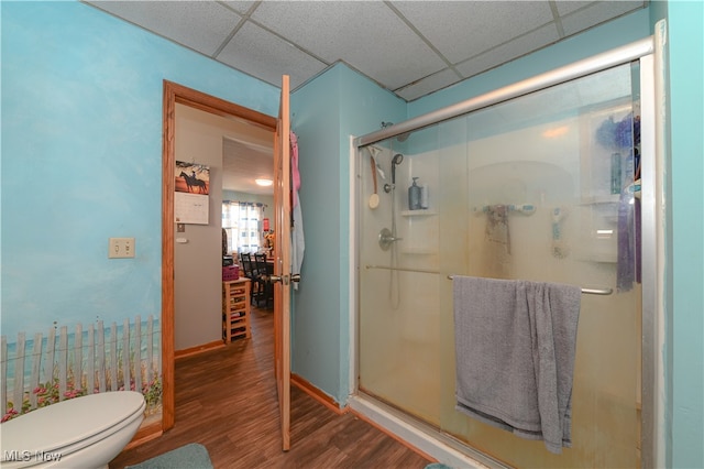 bathroom featuring a paneled ceiling, a shower with door, toilet, and hardwood / wood-style flooring