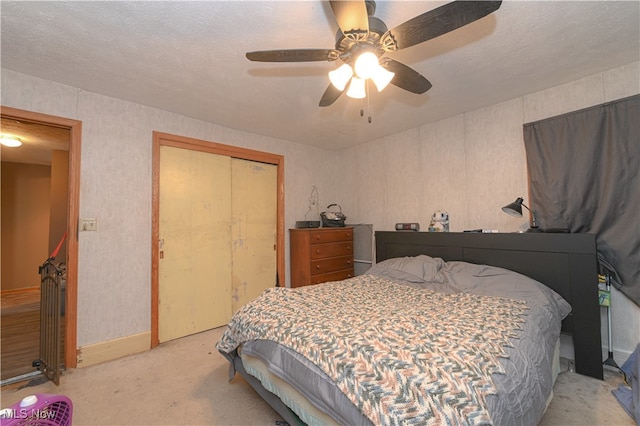 bedroom featuring light carpet, a closet, ceiling fan, and a textured ceiling