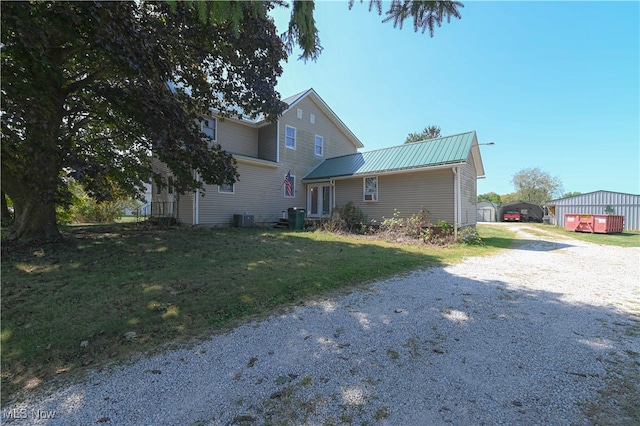 view of front of property with central AC unit, a front yard, and an outbuilding