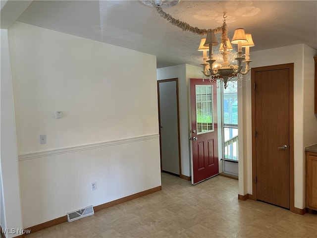 entryway with a textured ceiling and a notable chandelier