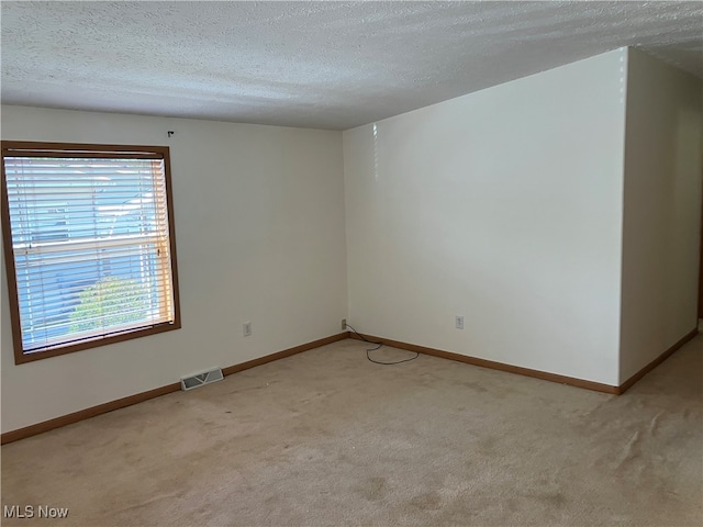 unfurnished room with a textured ceiling and light colored carpet