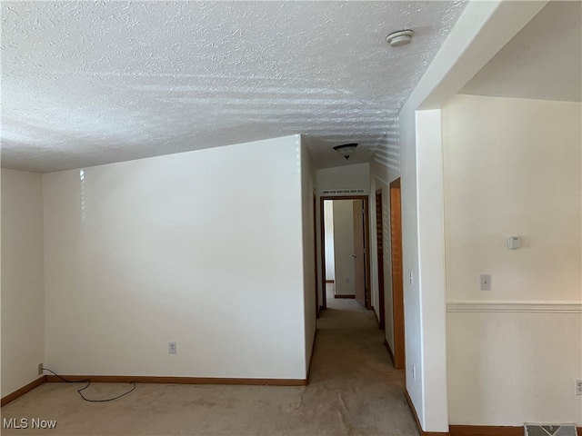 carpeted empty room with a textured ceiling and vaulted ceiling