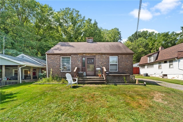 back of property with central AC and a lawn