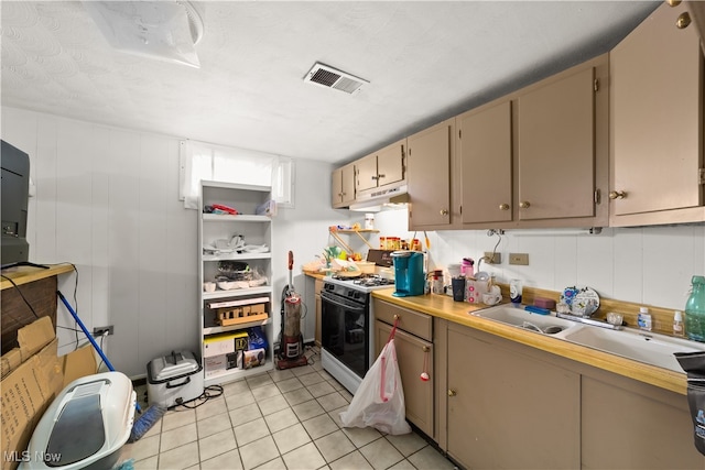 kitchen with a textured ceiling, white gas stove, light tile patterned flooring, and sink