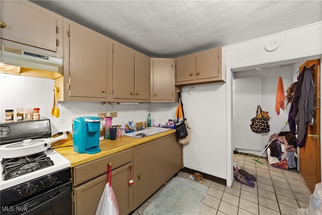 kitchen featuring a textured ceiling, white gas range oven, sink, and light tile patterned floors