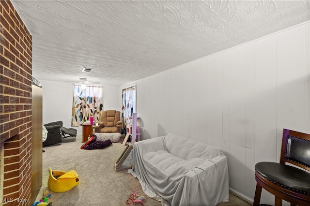 interior space featuring carpet flooring, a textured ceiling, and a brick fireplace