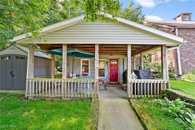 bungalow-style house with a porch and a storage unit