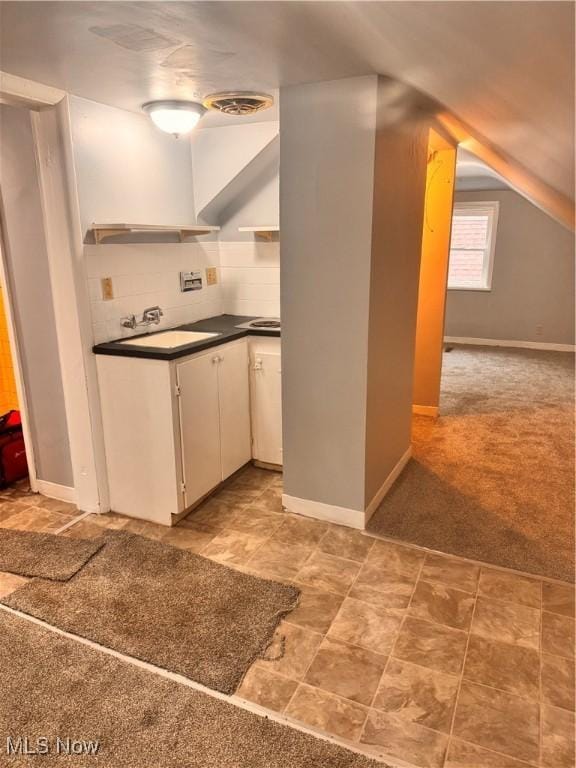 kitchen featuring backsplash, light colored carpet, vaulted ceiling, extractor fan, and white cabinets