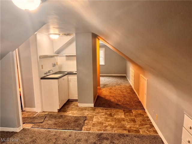 additional living space with dark colored carpet, vaulted ceiling, and sink