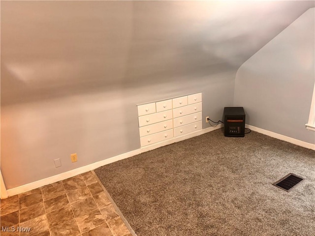 bonus room featuring dark colored carpet and vaulted ceiling