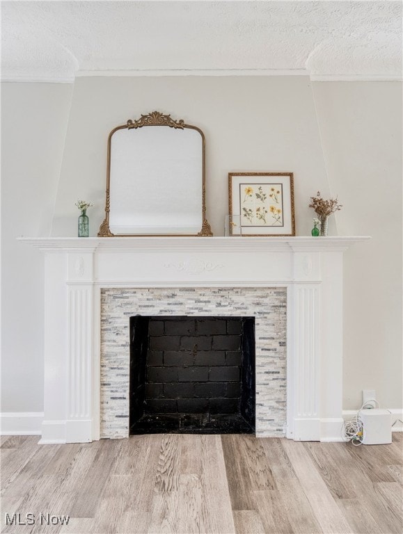 room details with a textured ceiling, a tiled fireplace, and hardwood / wood-style floors