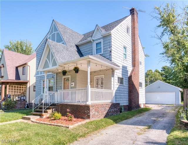 view of front facade featuring an outbuilding, a front yard, a garage, and a porch