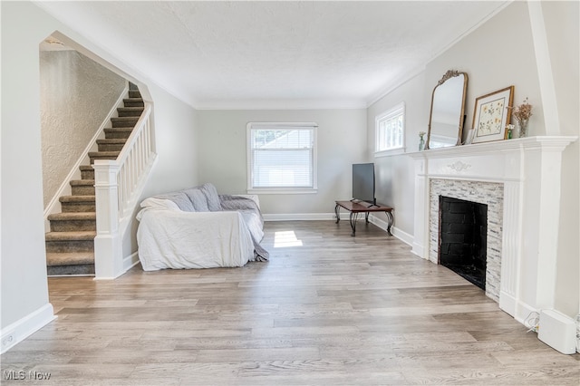 living room featuring a fireplace, ornamental molding, and light hardwood / wood-style flooring