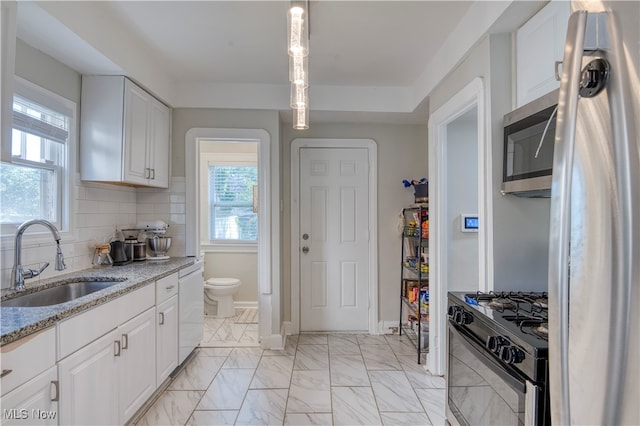 kitchen with appliances with stainless steel finishes, white cabinetry, and sink