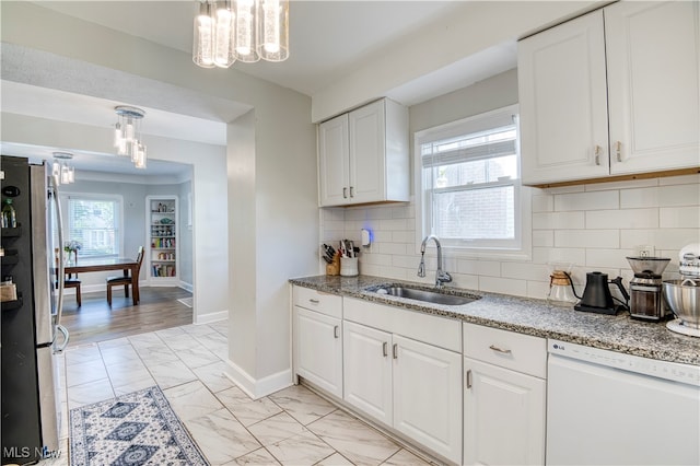 kitchen featuring stainless steel fridge, decorative light fixtures, white dishwasher, sink, and white cabinetry