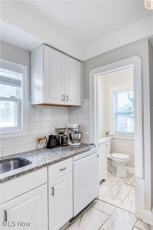 kitchen featuring white cabinets, white dishwasher, and a wealth of natural light