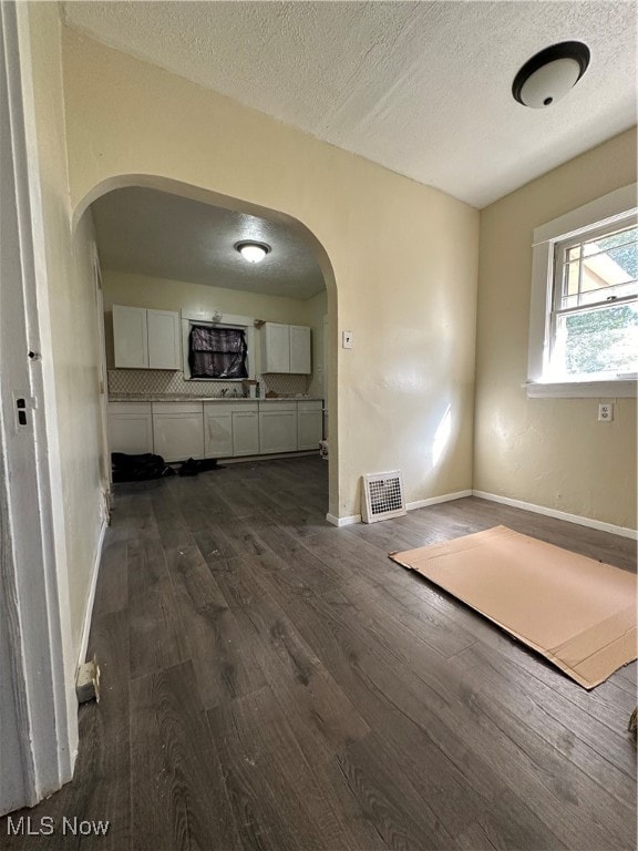 unfurnished living room with a textured ceiling and dark wood-type flooring